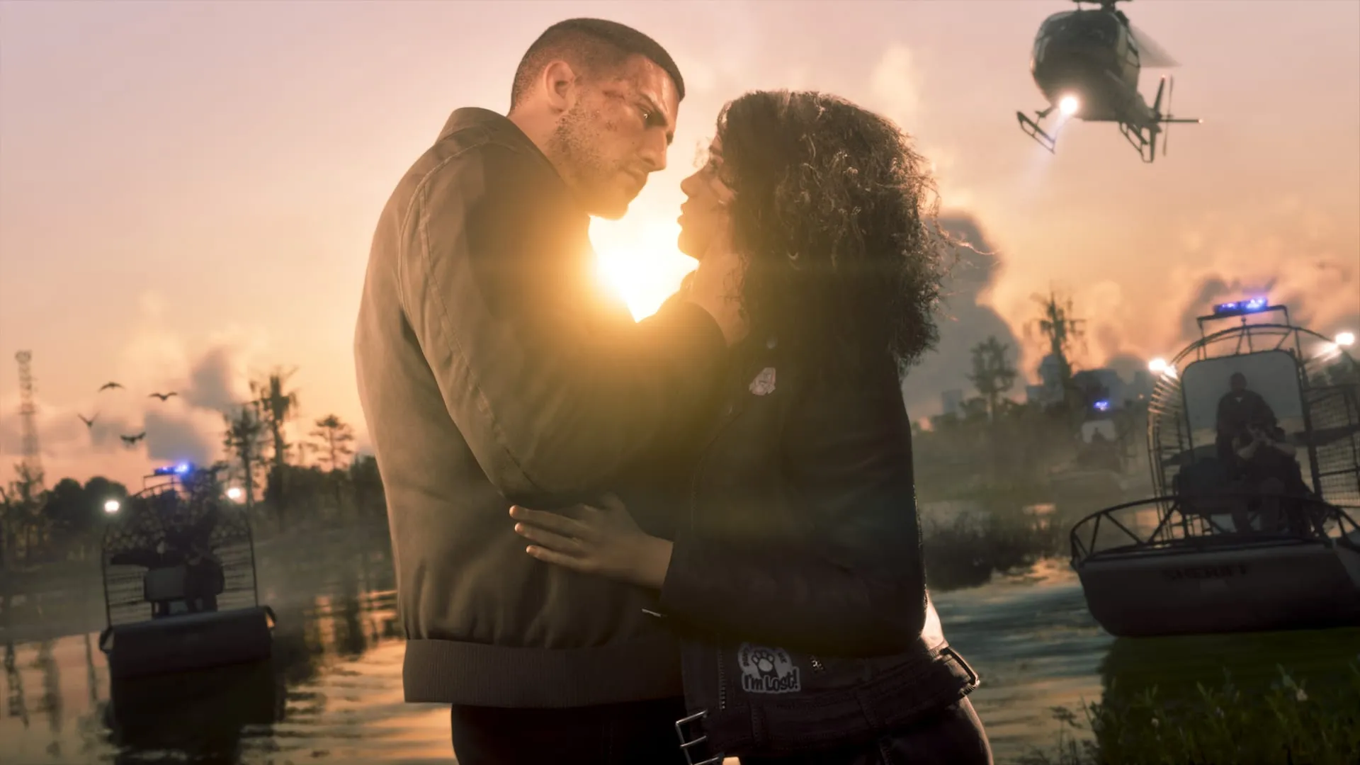 Jason et Lucia enlacés au coucher du soleil, devant des hydroglisseurs et un hélicoptère
